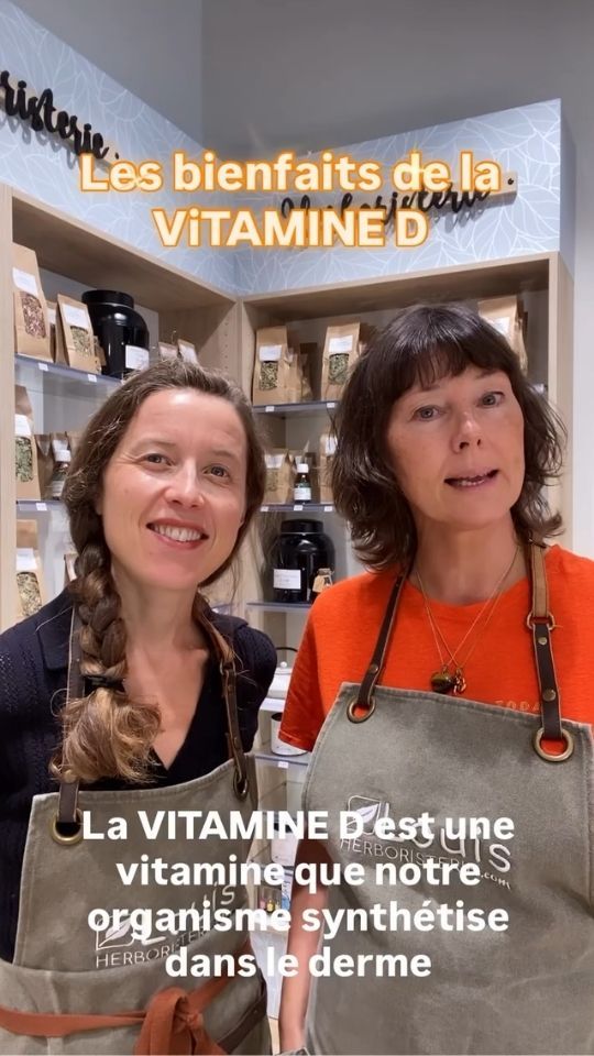 Deux femmes en tablier Louis Herboristerie devant des étagères de plantes, avec les textes incrustés Les bienfaits de la VITAMINE D et La VITAMINE D est une vitamine que notre organisme synthétise dans le derme.