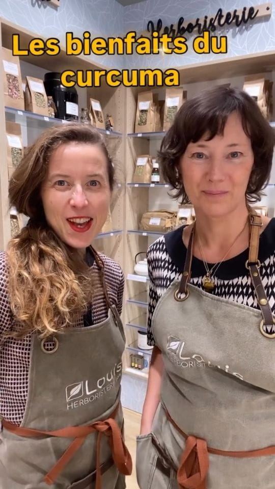 Deux femmes en tablier Louis Herboristerie devant des étagères de plantes, avec le texte incrusté Les bienfaits du curcuma.